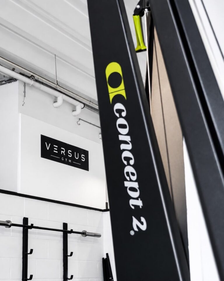 Enseigne Versus Gym fixée au mur de la salle, à côté d'un SkiErg Concept2