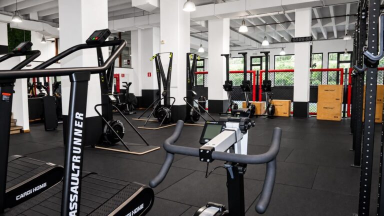 La salle Versus Gym vue depuis un vélo : SkiErg et rameurs alignés